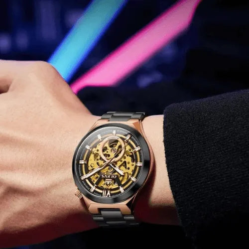 OLEVS Black Gold Skeleton Automatic watch worn on wrist, showcasing a gold skeleton movement, black case, and luminous hands under a transparent glass dial.