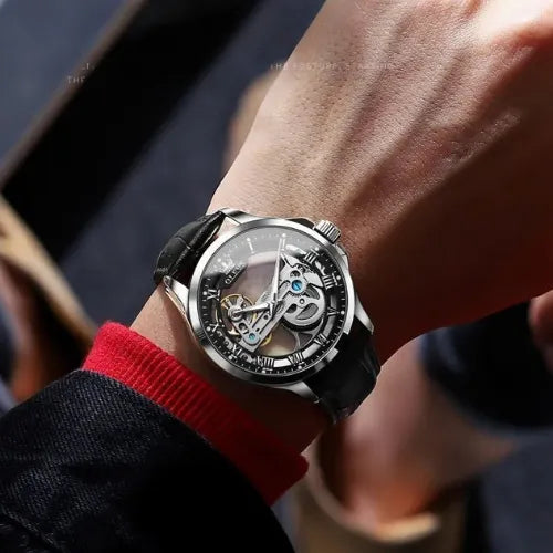 Men’s skeleton watch with black case and mechanical movement on wrist.