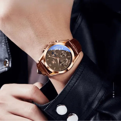 Brown leather chronograph watch with moonphase worn on a man’s wrist with black jacket.