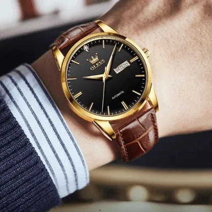 Stylish OLEVS automatic wristwatch with black dial and golden case, shown on wrist.