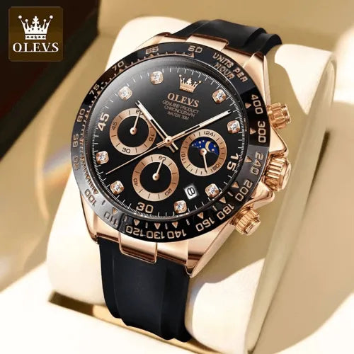 Close-up of the OLEVS Dominant Chronograph Black Rose watch with black dial, rose gold accents, diamond hour markers, and black silicone strap, displayed on a beige cushion.