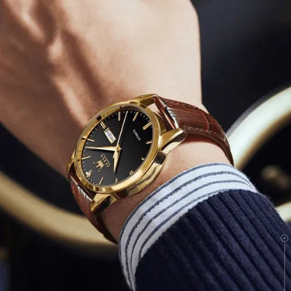 OLEVS men’s automatic watch with gold case, brown leather strap and black dial on wrist.