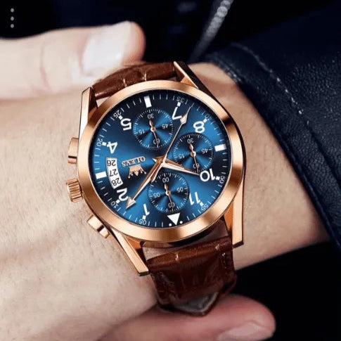 Fashionable OLEVS chronograph men’s wristwatch in gold with blue dial and leather strap styled on wrist.