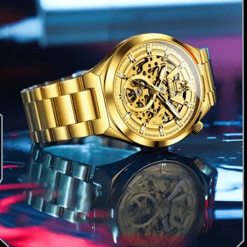 Stylish OLEVS gold skeleton automatic men’s watch photographed on reflective surface highlighting golden bracelet.