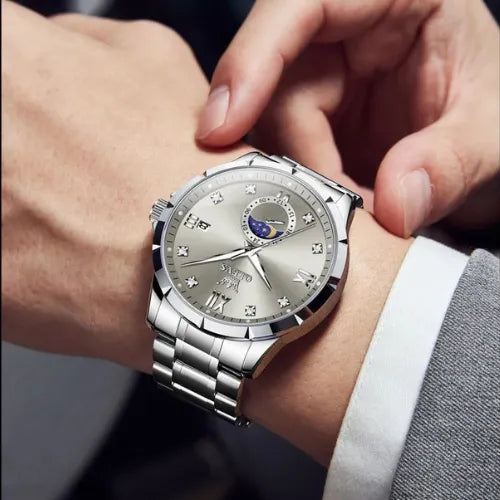 Stylish OLEVS men’s silver business quartz watch with moon phase, worn on wrist with grey suit.